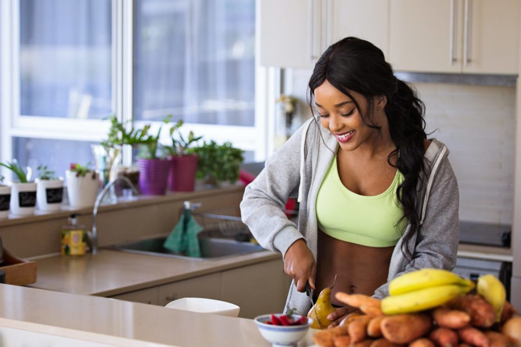 Jeune femme joyeuse préparant un bol de fruits