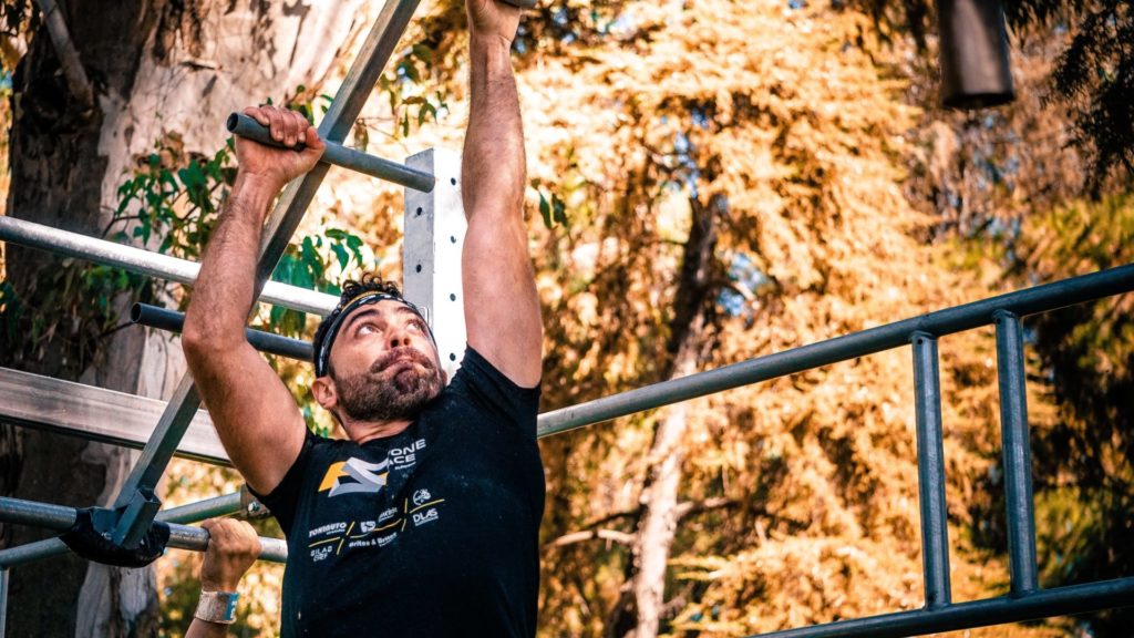 Un homme en teeshirt noir pendant la séance de monkey bars